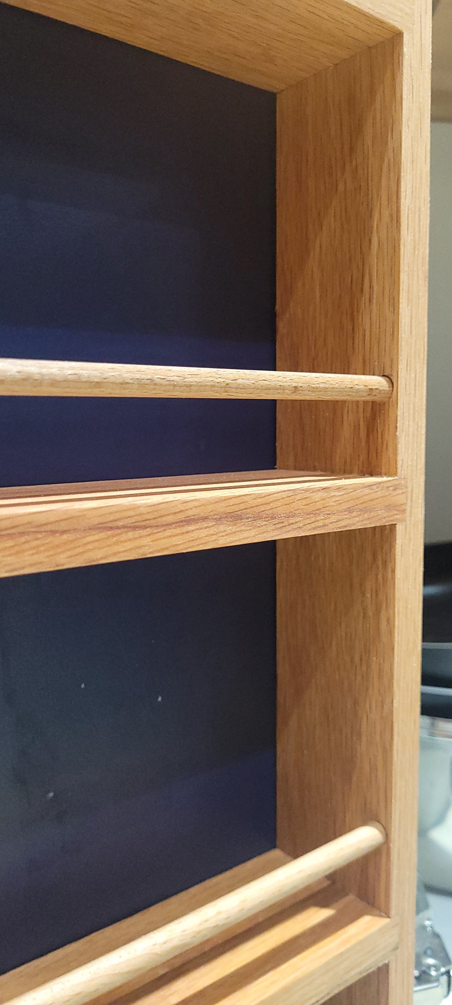 Closeup of slim 3 shelf solid oak spice rack with wooden rails