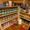 Solid pine spice racks with 3 shelves, in a corner, holding a range of herb and spice jars